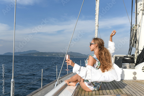 Beautiful young woman with champagne flute looking away while sitting on yacht