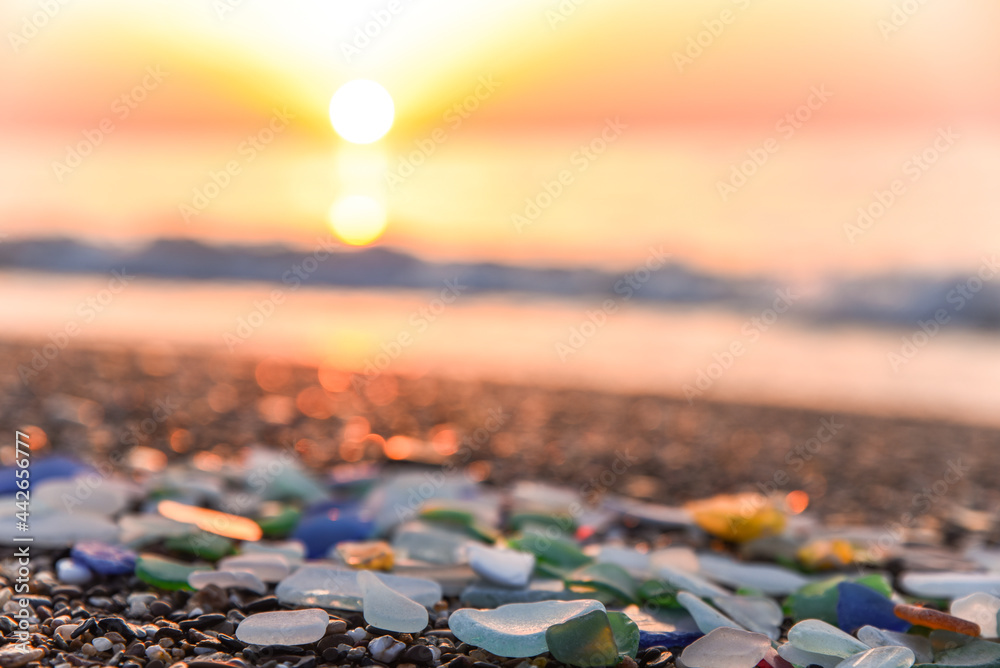 Beautiful colorful sea glass on beach at sunset, very suitable image for summer travel