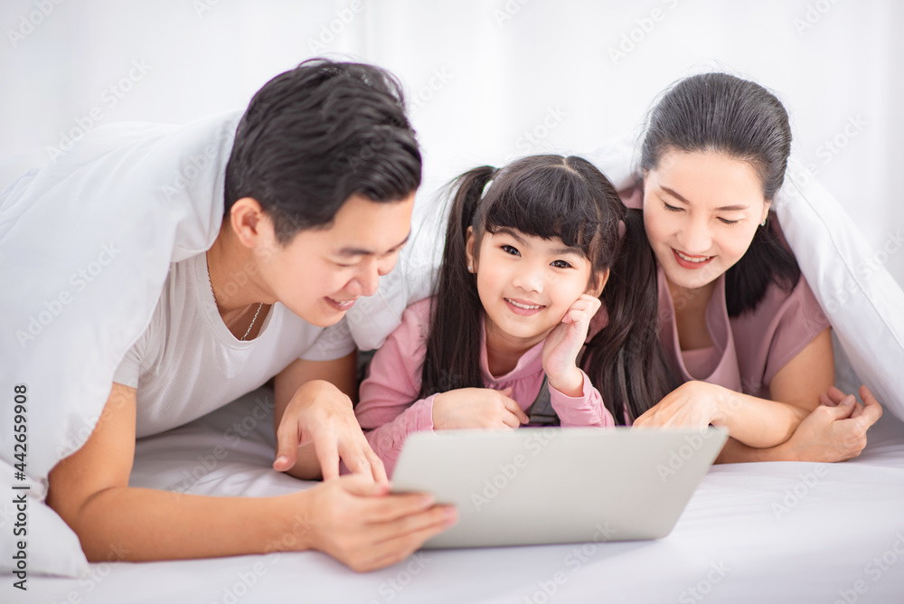 Closeup - Attractive asian family (mother, father, child daughter) smiling and using laptop computer together in home. Closeup - Attractive asian family (mother, father, child daughter) smiling and using laptop computer together in home.