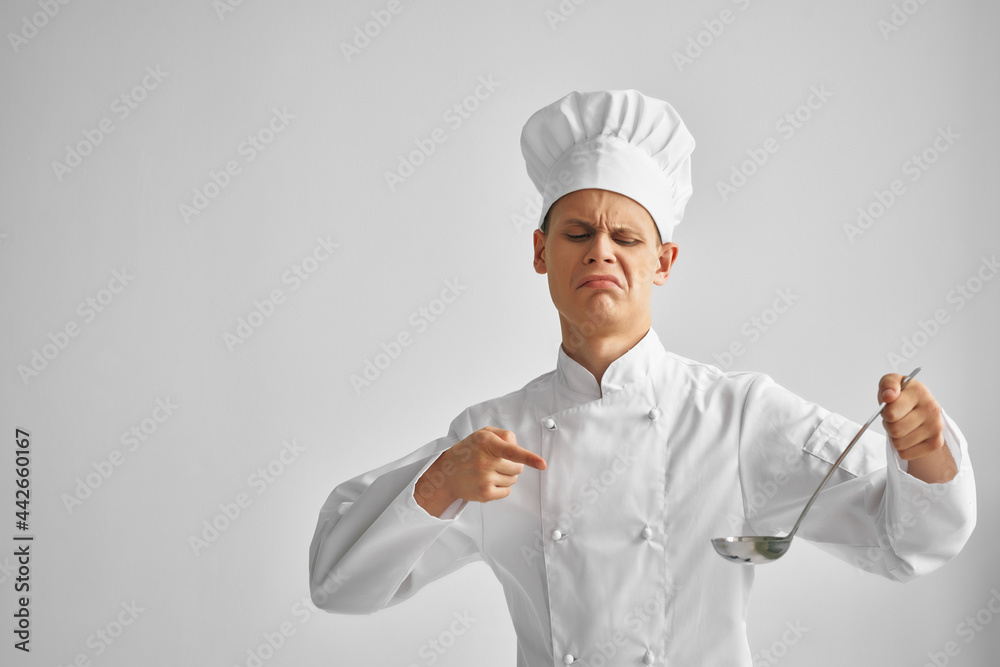 a man in a chef's uniform points a finger at a ladle a man in a chef's uniform points a finger at a ladle