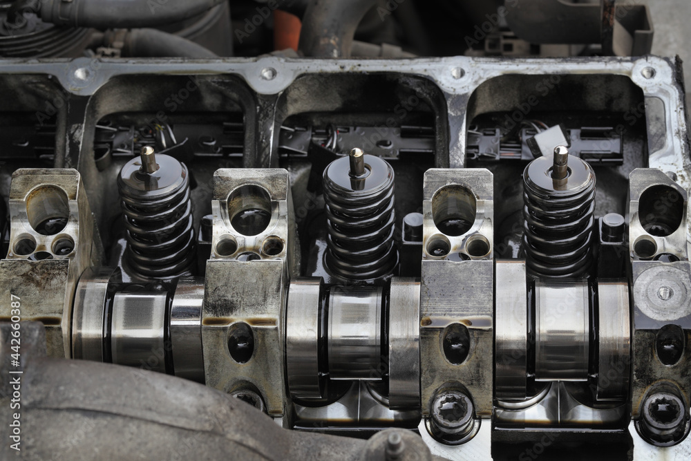 Detail of modern diesel engine repair, closeup of injectors in cylinder head with camshaft, selective focus 	