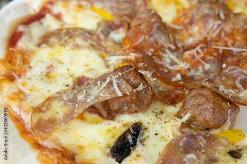 Selective focus and top view shot of original homemade thin pizza with a lot of melted cheese  sausage and pepperoni served in italian food restaurant table looks delicious but unhealthy fast food.