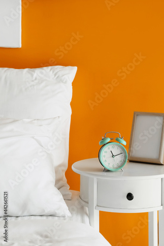 Alarm clock and frame on bedside table
