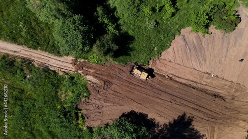 Dozer during clearing forest for construction new road. Aerial view of the bulldozer at forestry work and deforestation. Leveling the soil for construction or digging the foundation for a building
