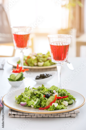 Plates with fresh Greek salad and glasses of wine on table in restaurant