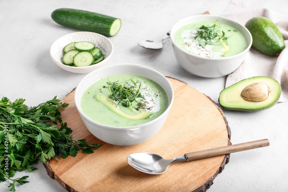 Bowls with green gazpacho and ingredients on light background Bowls with green gazpacho and ingredients on light background