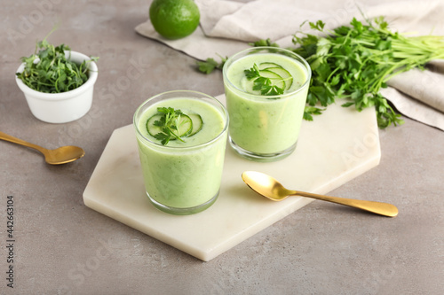Foto Glasses with green gazpacho, fresh sprouts and parsley on grey background