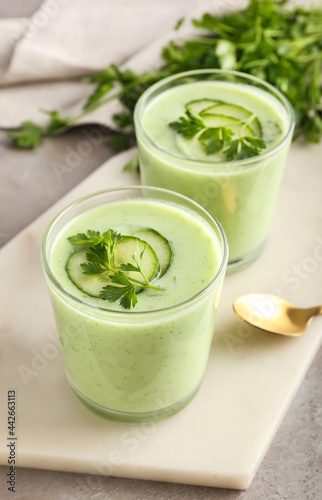 Glasses with green gazpacho on grey background