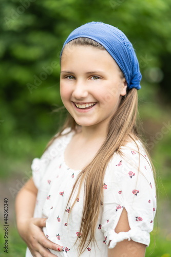 Porträt eines jungen, hübschen, nachdenklich Mädchens mit blauem Kopftuch im Wald. Lebensfreude, Glück, Gesundheit, Freiheit sind Motivation in der grünen, blühenden Natur.