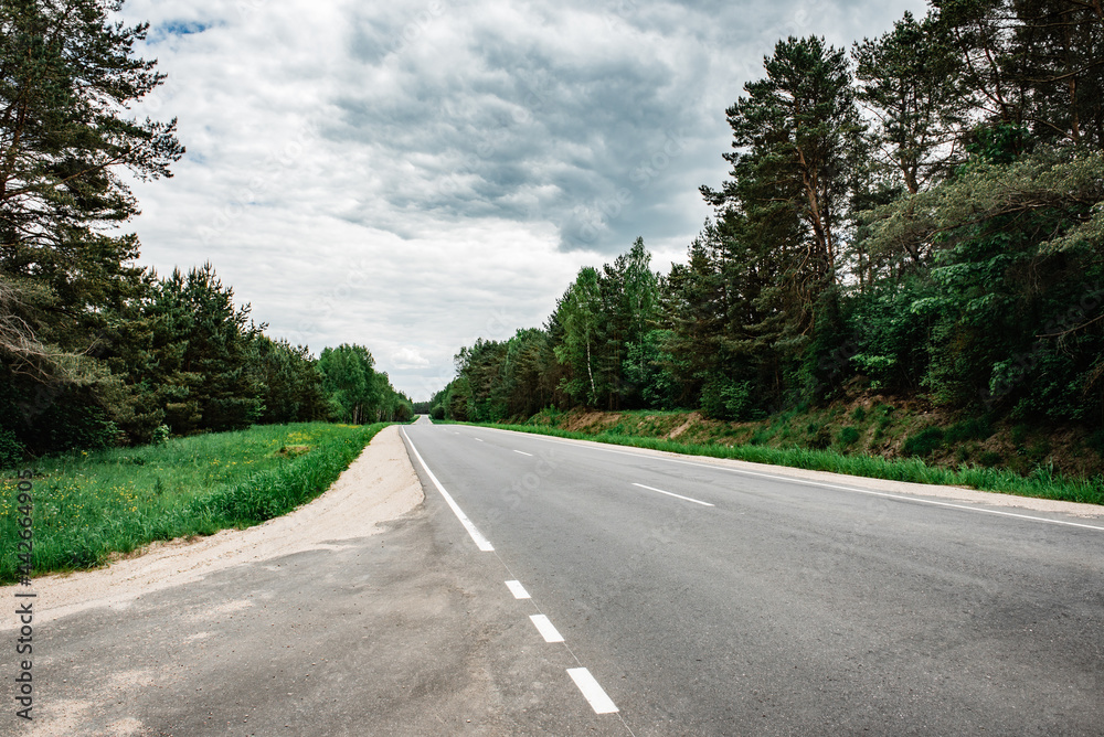 Empty country asphalt road near forest in summer time.