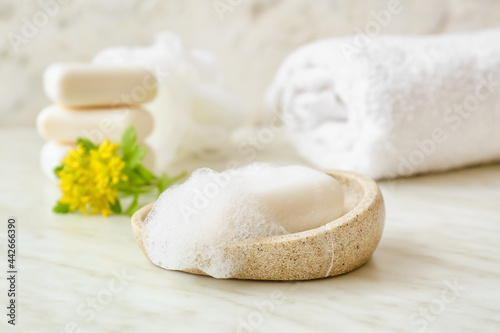 Bowl with soap bar on light background