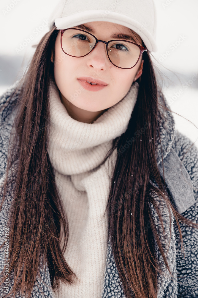 Portrait of an attractive girl dressed in stylish winter clothes. Woman posing for a photo on a snow-covered and icy lake in a local park Portrait of an attractive girl dressed in stylish winter clothes. Woman posing for a photo on a snow-covered and icy lake in a local park