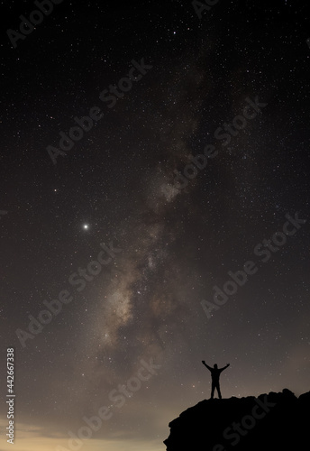 Milky Way. Night sky with stars and silhouette of a standing happy man with yellow light. Space background © kittipong