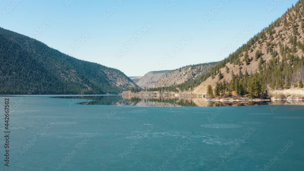 Aerial fly over semi frozen lake in a mountain valley in Fall Aerial fly over semi frozen lake in a mountain valley in Fall