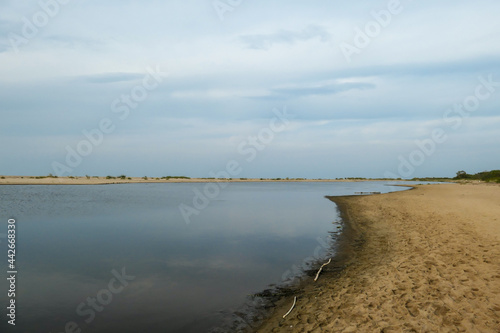 The coastal line of a sandy beach by the Baltic Sea on Sobieszewo island  Poland. The sea is gently waving. A bit of overcast. Solitude and serenity