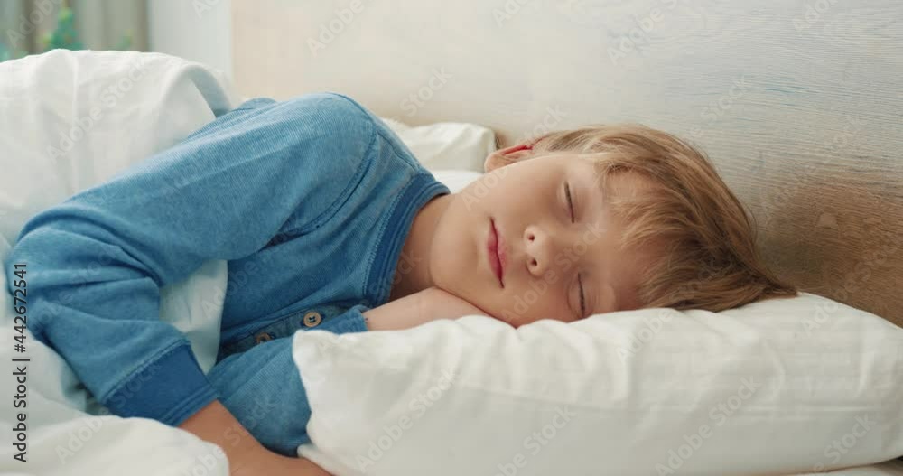 Close up of little cute preschool boy sleeping sweetly in bed in pajamas in morning time alone.