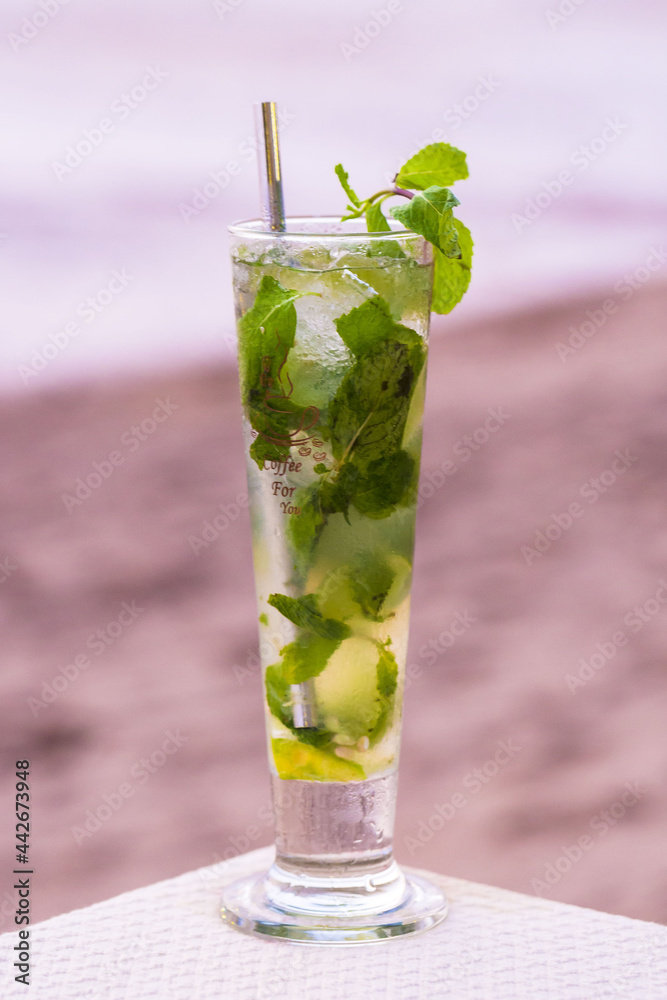Mojito Cocktail on a beach with a metal straw with a white sea view background Mojito Cocktail on a beach with a metal straw with a white sea view background