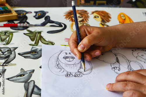 The animator draws with a pencil and draws characters from cartoons, comics or puppet shows. Mowgli's play. Preparing to make a doll. The designer creates sketches. Comics, cartoons, puppet theater photo