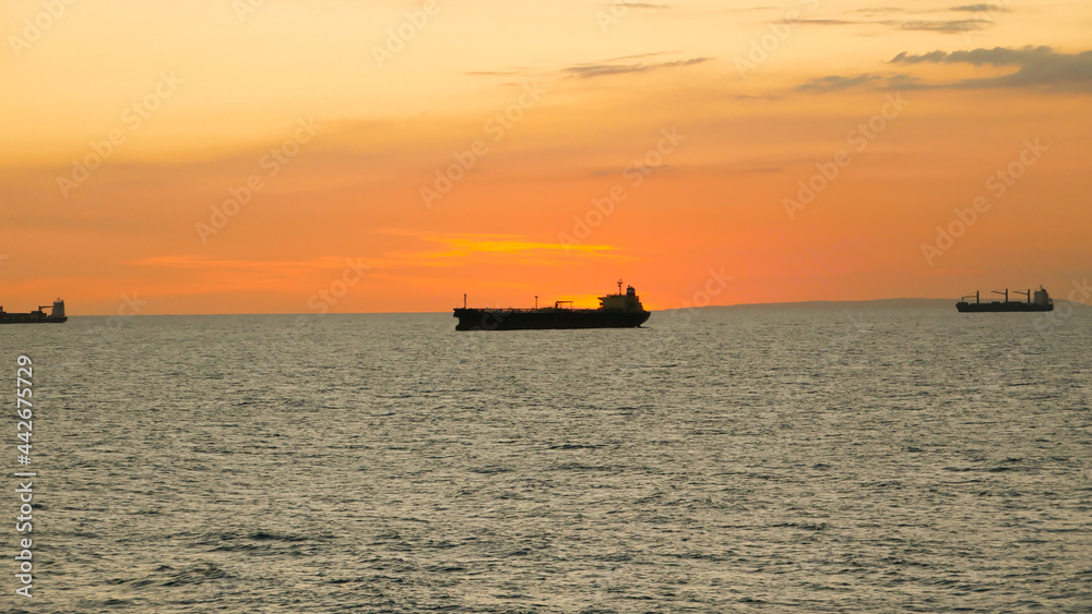 Sunset in the sea with view of tanker vessel on the horizon line