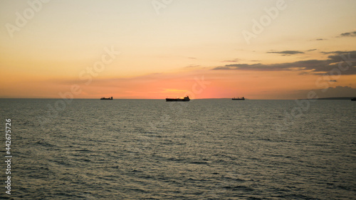 Sunset in the sea with view of tanker vessel on the horizon line © Genya