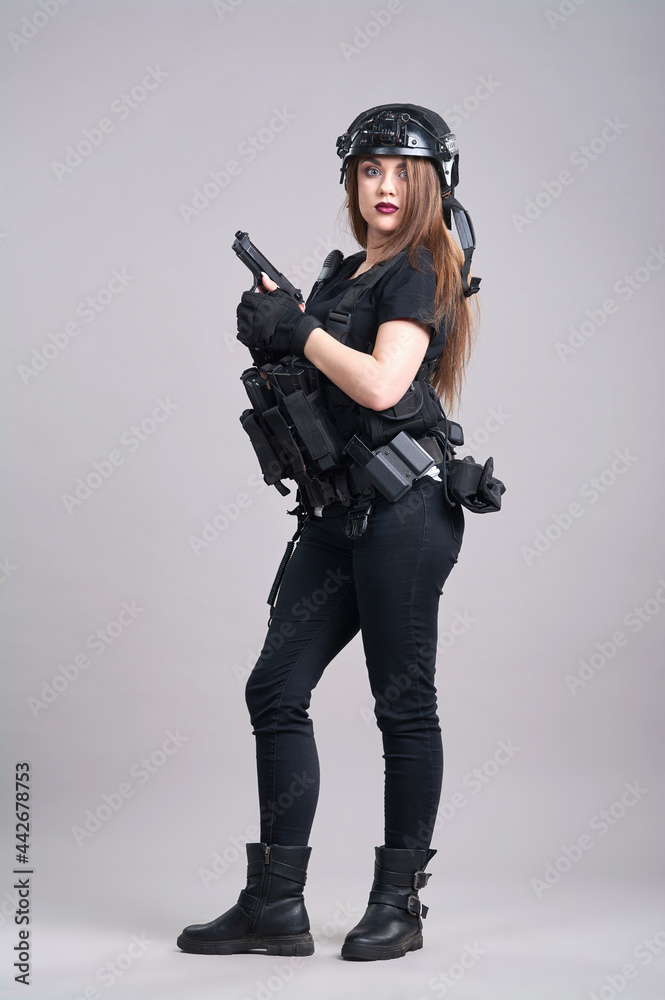 A young woman is sitting with a gun in her hands on a gray background A young woman is sitting with a gun in her hands on a gray background