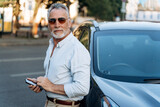 Portrait of senior man outdoors. Middle aged man standing near his SUV car