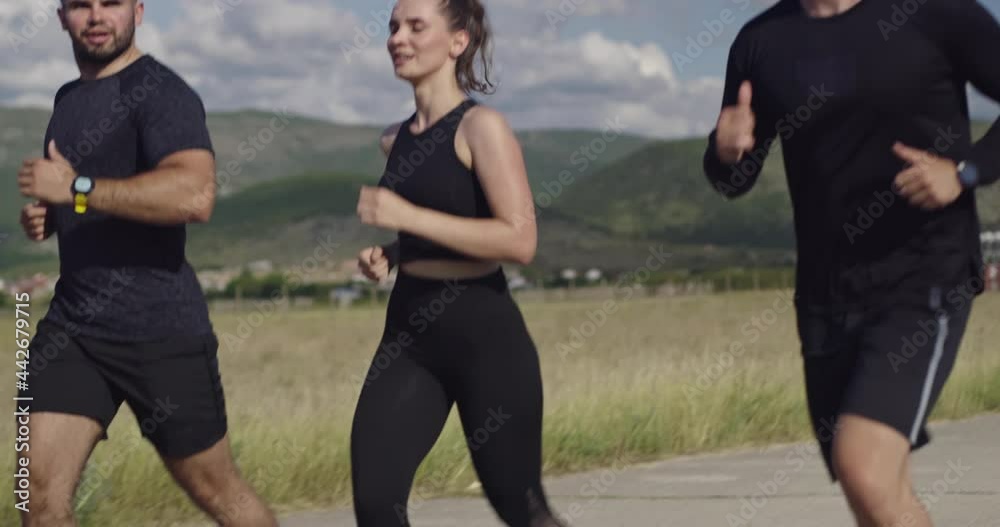 Multiethnic group of athletes running together on a panoramic countryside road. Diverse Team of joggers on morning training. Multiethnic group of athletes running together on a panoramic countryside road. Diverse Team of joggers on morning training.
