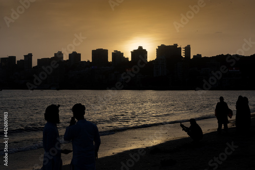 Silhouettes of people and skyscrapers during sunset at Marine drive Beach in Mumbai Maharashtra India 