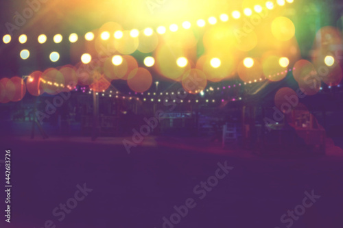 фотографія blurred bokeh light with yellow string lights decor in beach restaurant at dusk