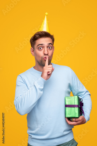 Funny man with birthday gift making shh sign