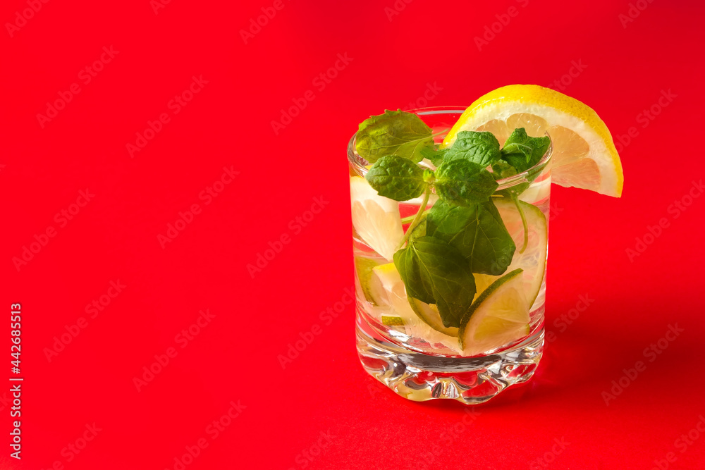 Citrus water with lemon, lime and mint. A glass of lemonade on a red background. Vitamin drink. Healthy diet. Concept.. Citrus water with lemon, lime and mint. A glass of lemonade on a red background. Vitamin drink. Healthy diet. Concept..