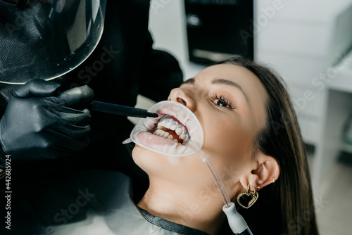 Dentist putting photosensitive paste during teeth treatment