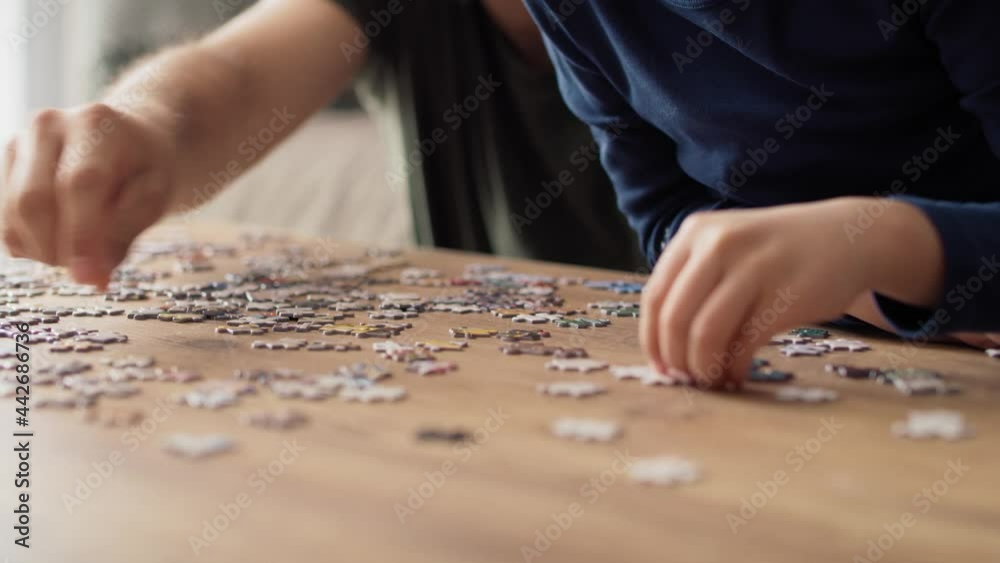 Close up video of father solving jigsaw puzzle with son. Shot with RED helium camera in 8K. Close up video of father solving jigsaw puzzle with son. Shot with RED helium camera in 8K.