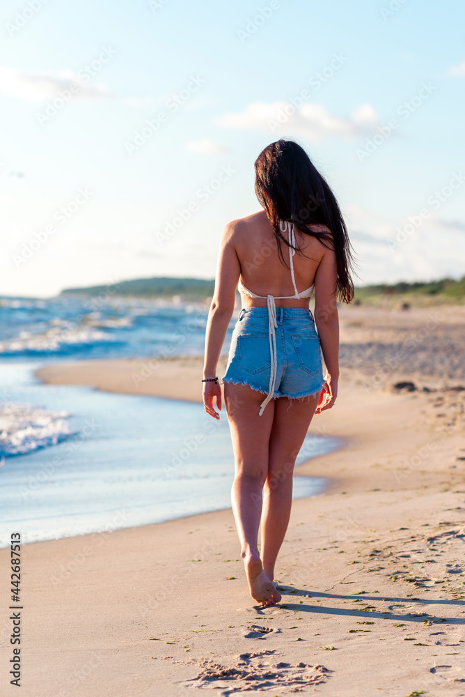 Yong woman traveler relaxing on a perfect summer beach.Beautiful woman walking along the coast,summer warm nice day.