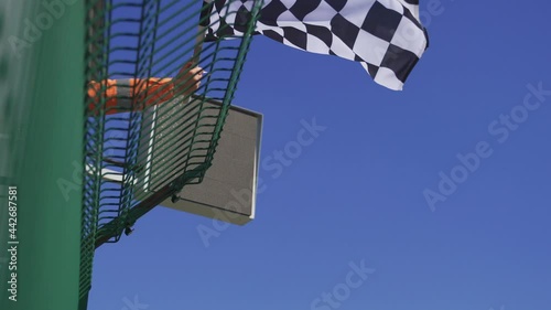 Man holding and waving Checkered race at finish line on a raceway. Victory, achievement, success and sport concept. 