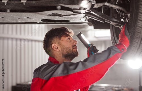 Technician checking car chassis in workshop photo