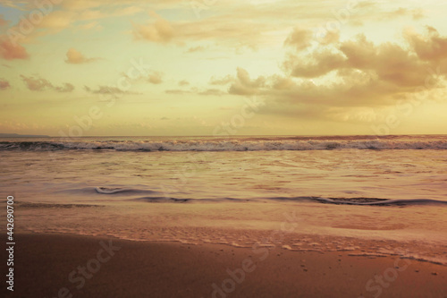 A beautiful yellow grey beach at golden hour. Ocean shore in soft light of evening sun. Natural background for design.