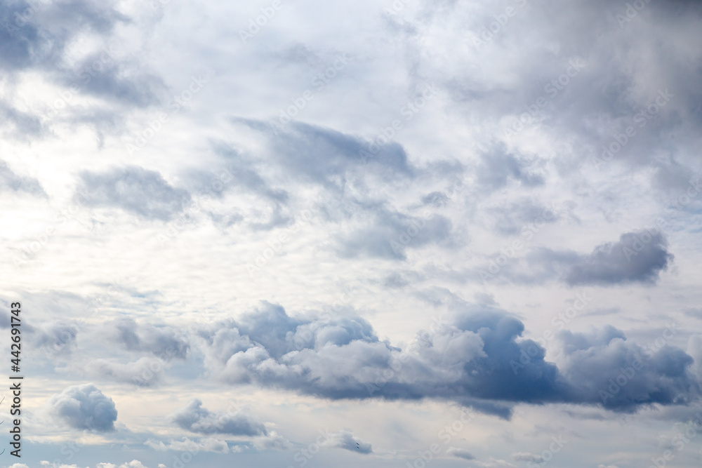 Fototapeta premium Stormy sky background with sun shining through the dense set of cumulus clouds scattered by the wind