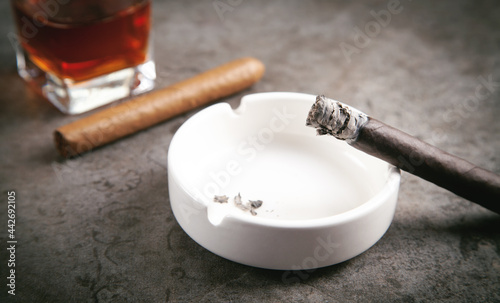 Glass of whisky, ashtray and cigars on the table.