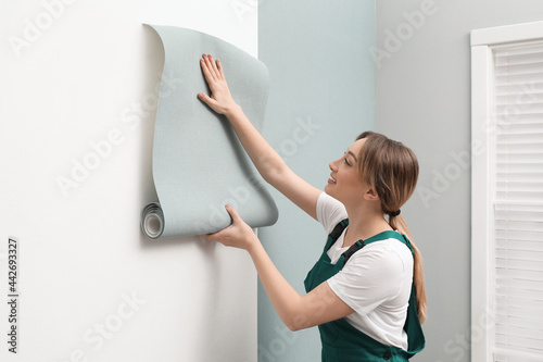 Obraz na plátne Worker hanging stylish wall paper sheet indoors