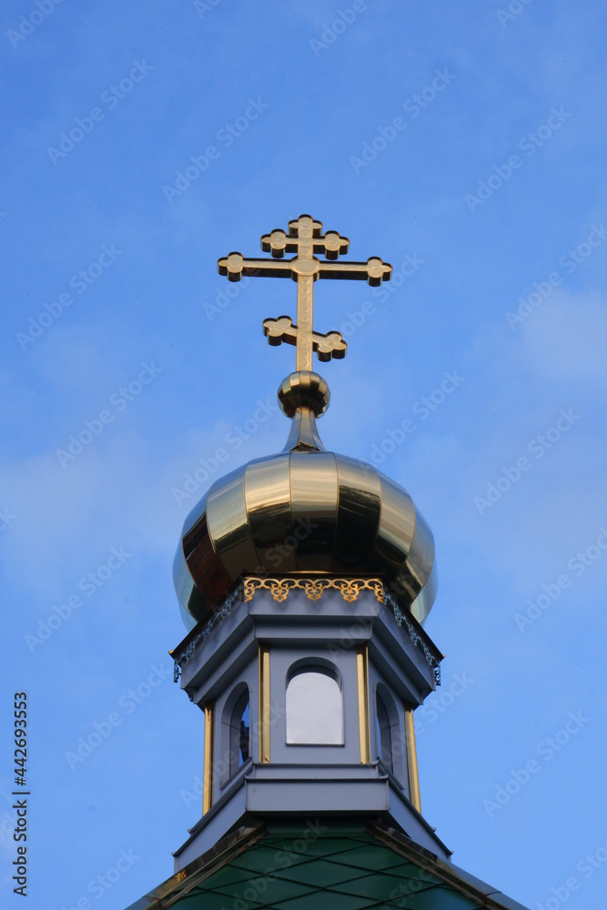 Golden cross on the dome of the church against the blue sky Golden cross on the dome of the church against the blue sky