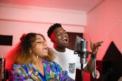 Black friends singing into microphone in studio photo