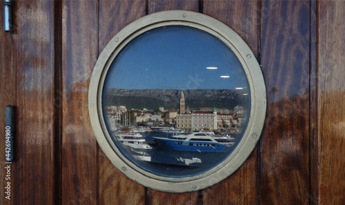 the picturesque harbor is reflected through the porthole of the ship, Split, Croatia