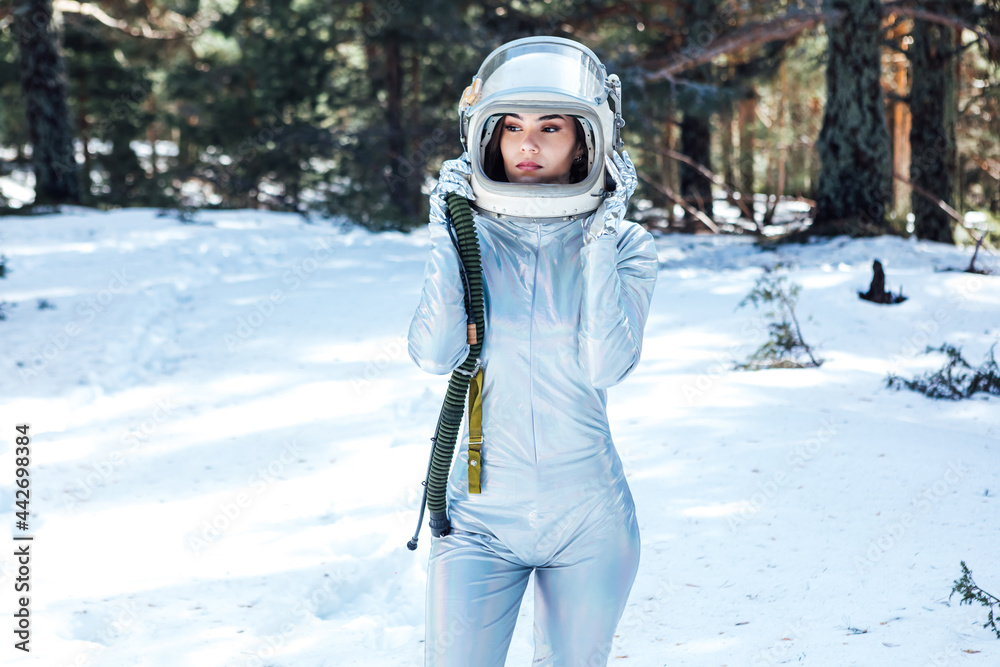 Determined female in space helmet standing in snowy forest Determined female in space helmet standing in snowy forest