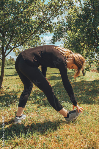 Young woman in sportswear doing exercises in nature. Healthy lifestyle concept.