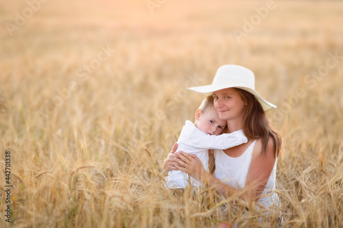 Beautiful American mother and son in a field with wheat, looking at the ears. Summer, organic food and nature