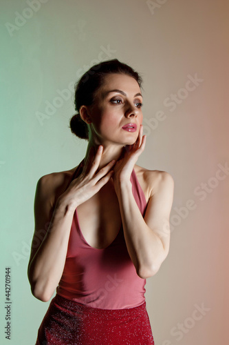 Colored background, neon lights, studio shot. Portrait of a young elegant brunette woman in a beautiful dress. Vertical photo, place for text. © Yuliia