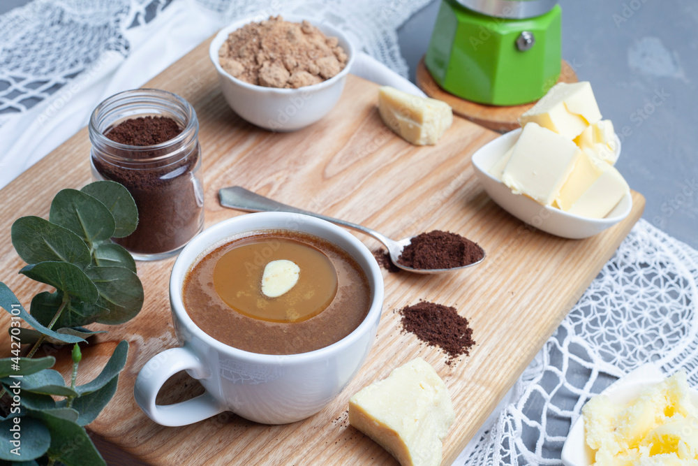 KETOGENIC KETO DIET DRINK. Coffee and cocoa mixed with ghee. Cup of bulletproof coffee with cocoa and ingredients on wooden background KETOGENIC KETO DIET DRINK. Coffee and cocoa mixed with ghee. Cup of bulletproof coffee with cocoa and ingredients on wooden background