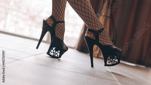 Girl's legs in high heels - strips in a light room