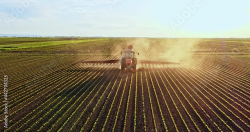 Tractor on field spraying crop with pesticides photo